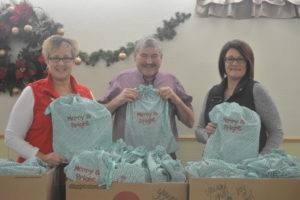 Susie Mann, left, and Kelly Kellish, right are independent contractors with Initials, Inc. and donated bags filled with toys and other items for New Life Ministries first ever Toys for Tots program. Pastor of the church, Mark Granger, is pictured in the center. Beth Scott | Beacon