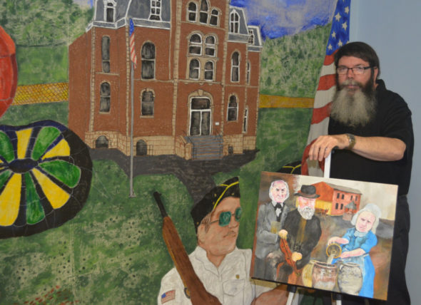 Ron Cummings will have his art work on display at the West Lafayette Branch Library during the month of June. He is pictured here with a painting he is working on and a mural he created that is on display in his classroom at the Church of Christ. Josie Sellers | Beacon